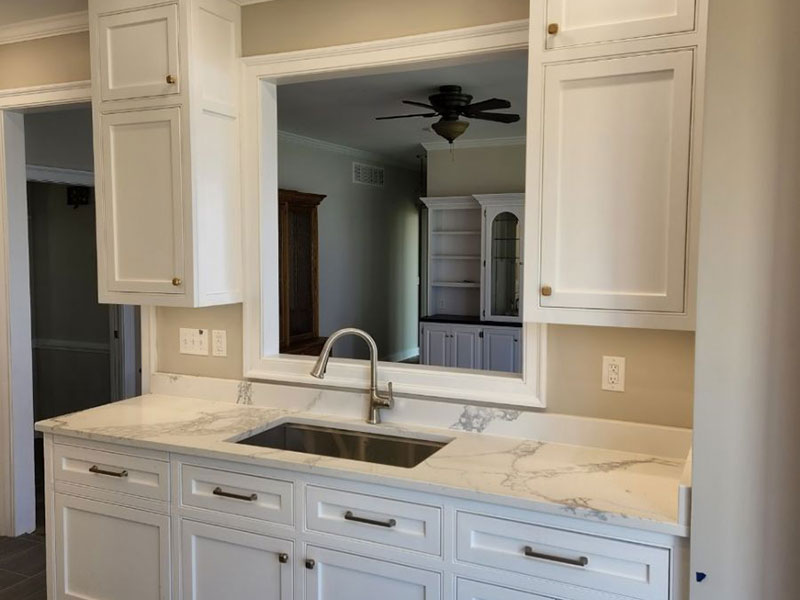 Kitchen sink counter with brand new white cabinets installed by Walnut Tree Custom Cabinets & Millwork underneath the counter and to either side of the sink on top